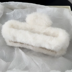 Close-up of soft white plush hair claw clip featuring fluffy faux fur on tissue paper