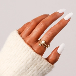 Détail de bagues dorées empilées avec motifs étoile et soleil sur maille blanche
