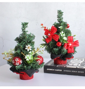 Close-up of mini desktop Christmas trees with red bows and sequined base on white desk