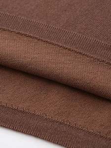 Vue macro montrant la texture du tricot côtelé marron foncé et les coutures fines