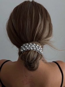 Detail of silver alloy hair tie with pearls and crystals on a braided bun hairstyle