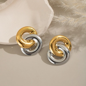 Minimalist gold and silver interlocking hoop earrings on an elegant beige studio background