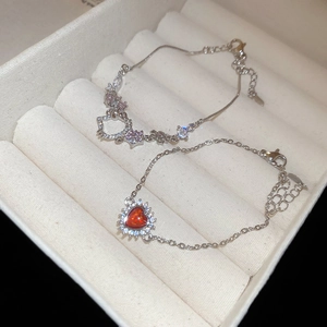 Detail of silver chain bracelets featuring a Hello Kitty charm and red heart zircon stone
