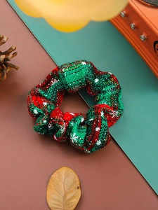 Close-up of red and green plaid fabric scrunchie with snowflake patterns and pine cones