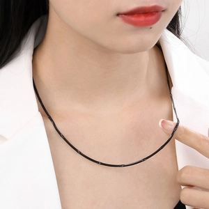 Dettaglio di una catena a serpente nera da 2,2 mm con texture liscia sul collo di una modella