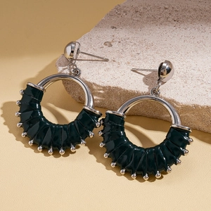 Macro detail of dark green leather wrapped C-shape hoop earrings on a stone base