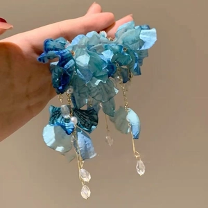 Close-up of blue floral chiffon hair accessory with white pearls and crystal tassels