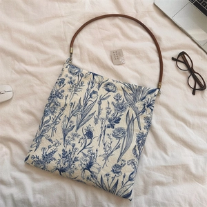 Detailed top view of retro blue floral canvas bag with round brown handle on white cloth