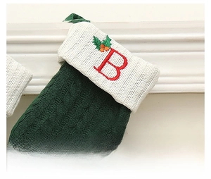 Détail de la chaussette de Noël en tricot torsadé vert avec lettre B brodée et houx rouge