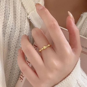 Close-up of a gold beaded open ring on a model wearing a white knit sweater