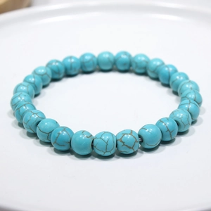 Close-up of turquoise beaded bracelet with natural brown veins on a white ceramic tray