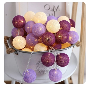Detail of warm glow LED cotton ball string lights in purple and cream for room decor