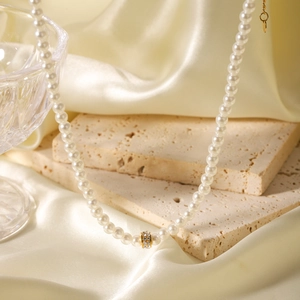 French style pearl necklace with gold diamond-set ring pendant on silk and stone