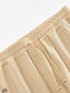 Detail of linen pants featuring an elastic drawstring waistband and an amber button