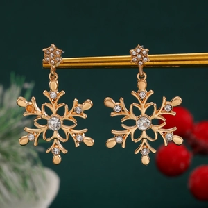 Close-up of golden snowflake earrings with sparkling rhinestones and Christmas decor