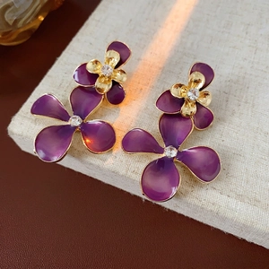 Purple enamel flower earrings with gold petals and sparkling crystal center in macro view