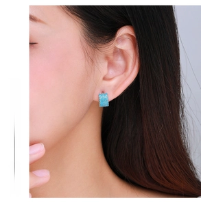 Close-up of sky blue turquoise earrings worn by a model in a minimal setting