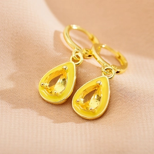 Macro view of gold teardrop earring with yellow crystal inlay and enamel trim