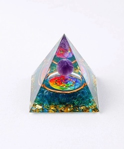 Macro detail of Orgone pyramid with purple crystal sphere and blue stones in resin