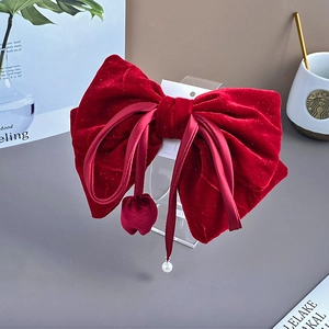 Detailed close-up of velvet red bow hair clip with tassel pearls and rhinestone accents