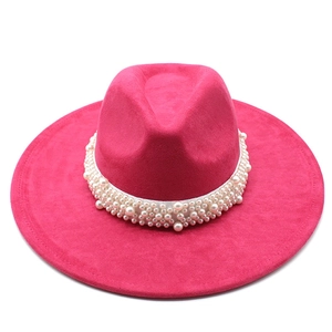 Detail of fuchsia suede fedora with a decorative white pearl band on flat brim
