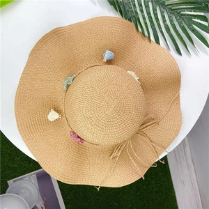 Top view of straw sun hat featuring colorful mini tassels and a woven bow detail