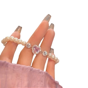 Bracelet perles avec zircon cœur rose et détails argentés porté élégamment au poignet