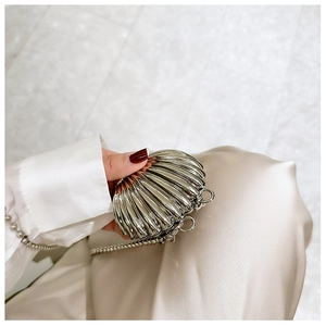 Macro shot of silver shell-shaped mini bag with metallic texture and beaded chain