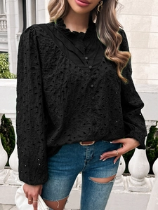 Detail of black long-sleeved shirt featuring intricate hollow embroidery and ruffled collar