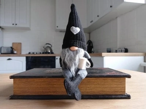 Knitted faceless gnome doll with coffee theme sitting on vintage books for home decor