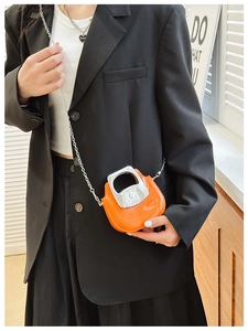 Mini orange crossbody bag with silver chain and metal handle worn with a black blazer