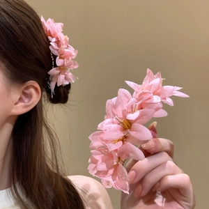 Dettaglio ravvicinato di un dolce fermaglio per capelli a fiore di stoffa rosa con rugiada