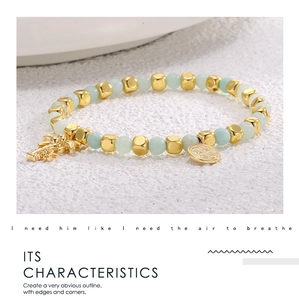 Detailed close-up of 14k gold plated square beads and light green stone beads with palm tree charm