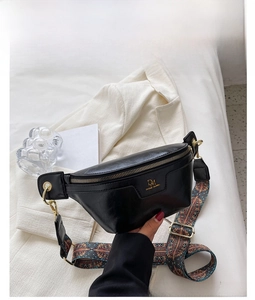 Detail of black faux leather chest bag with a colorful ethnic style patterned strap