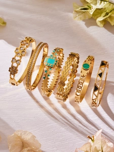 Detail view of six gold-plated stainless steel bracelets with geometric textures and stones