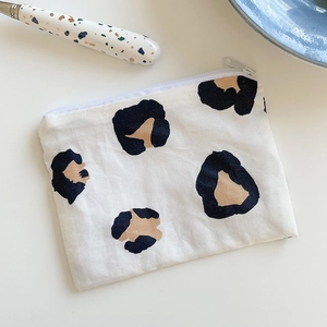 Flat leopard print cotton coin purse with zipper closure on a white minimalist tabletop