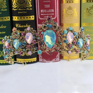 Macro shot of vintage gold bridal crown with colorful crystals on retro book background