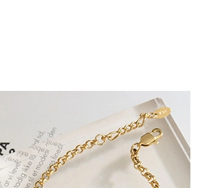 Detailed close-up of a gold chain with a lobster clasp and oval metal tag on an acrylic block