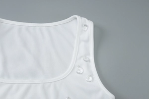 Macro detail of white ribbed tank top neck with decorative teardrop-shaped beads