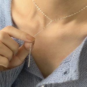 Macro detail of minimalist S925 sterling silver chain with a sleek vertical bar pendant