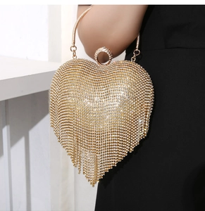 Close-up of golden heart-shaped evening bag with sparkling rhinestones and fringe