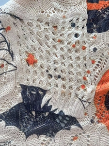 Détail de pull en maille ajourée beige avec motifs de chauve-souris d'Halloween