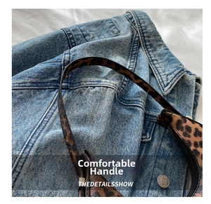 Detail view of the sleek leopard print crescent handbag with slender black carrying straps