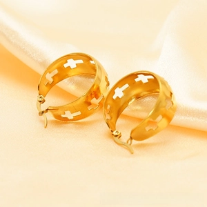Detail of gold chunky hoop earrings featuring hollow cross patterns on silk fabric