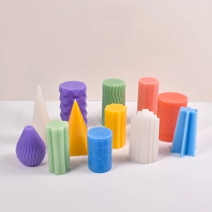 Collection of colorful geometric candles with ribbed and faceted textures in soft tones
