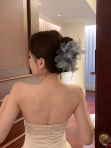 Elegant blue feather hair claw clip for bun hairstyles on model back view in soft lighting