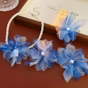 Detailed close-up of the pearl necklace and floral hair clips on an aesthetic wood background