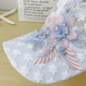 Close-up of white lace baseball cap with 3D floral embroidery and pearl accents