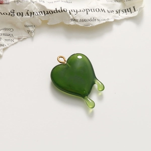 Detailed view of a translucent green melting heart charm with a golden metal loop