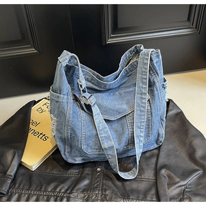 Détail d'un sac cabas en denim bleu vintage avec poches sur une veste en cuir noir